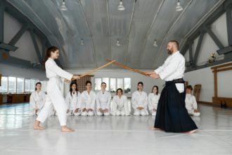 Martial arts master teaching young student to fight with wooden sword
